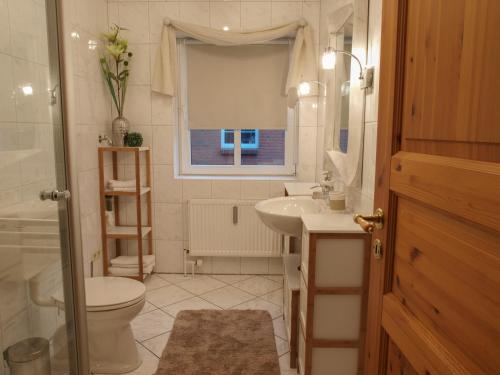 ein Bad mit einem Waschbecken, einem WC und einem Fenster in der Unterkunft Apartment Godewind in Dagebüll