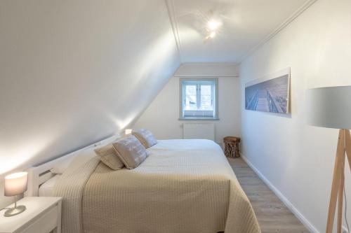 ein weißes Schlafzimmer mit einem Bett und einem Fenster in der Unterkunft Reethus Hans in Husum