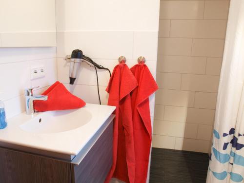 ein Bad mit einem Waschbecken und roten Handtüchern in der Unterkunft Ferienwohnung Diek in Humptrup