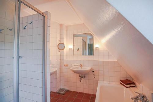 ein Bad mit einem Waschbecken, einer Dusche und einem Waschbecken in der Unterkunft Reethus Jan in Husum