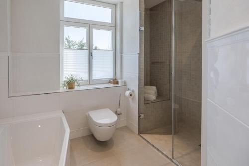a white bathroom with a toilet and a shower at Strandläufer in Husum