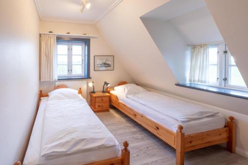 two beds in a room with two windows at Reethus Ulla in Husum