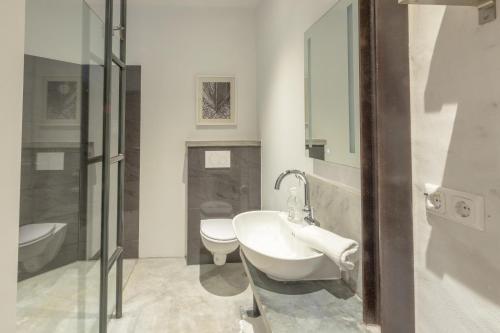 a bathroom with a sink and a toilet and a mirror at Apartmenthaus Tönning Sanddüne in Tönning