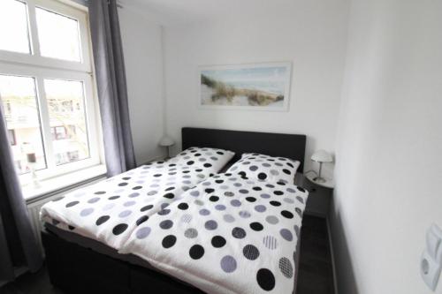 Schlafzimmer mit einem schwarzen und weißen Bett und einem Fenster in der Unterkunft Apartment Roock in Wyk auf Föhr