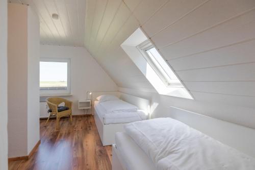 フーズムにあるDeichblickのベッド2台と窓が備わる屋根裏部屋です。