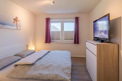 a bedroom with a bed and a flat screen tv at Nordlicht in Breklum