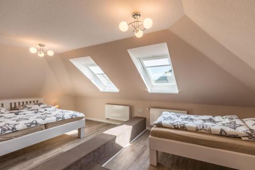 a attic bedroom with two beds and two windows at Schobüller Seestern in Husum