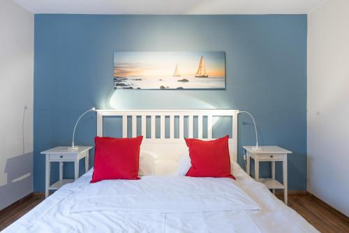 um quarto azul com uma cama branca com almofadas vermelhas em Lütte Stuuv im Schlossgang em Husum