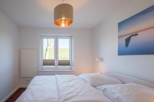 een slaapkamer met een wit bed en een raam bij Altes Schäferhaus in Nordstrand