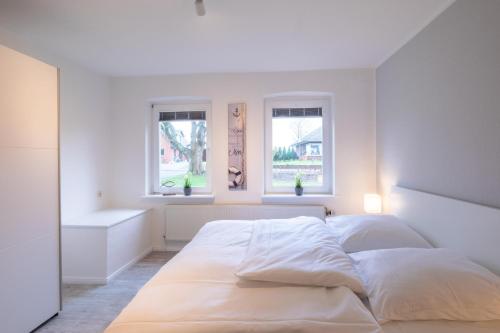 a white bedroom with a bed and two windows at Krokusliebe in Husum