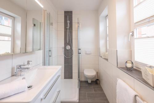 a white bathroom with a sink and a toilet at Lütte Jung in Husum