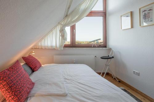 a bedroom with a white bed with a window at Käpt'n Cook 09 in Nordstrand