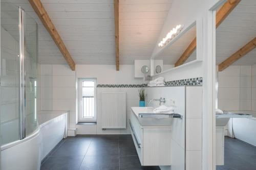 een witte badkamer met een wastafel en een spiegel bij Fofteinbutze twee in Nordstrand