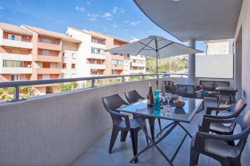 - une table avec des chaises et un parasol sur le balcon dans l'établissement L'orangeraie Calvi centre à 300m de la plage et du port parking privé, à Calvi
