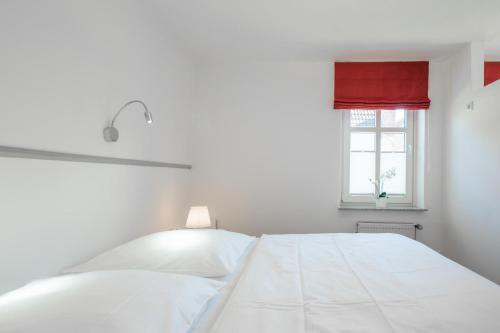 Cama blanca en habitación blanca con ventana en Dat lütte Huus - Wohnung 2, en Husum