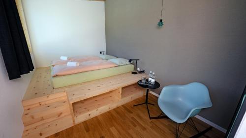 a bedroom with a bed on a wooden platform with a chair at Laax wellnessHostel3000 in Laax
