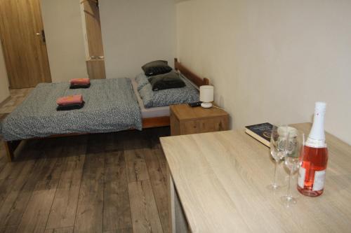 a room with two beds and a table with wine glasses at Andriš Apartmány in Spišské Bystré