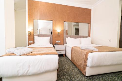two beds in a hotel room with two mirrors at The Green Park Diyarbakir in Diyarbakır