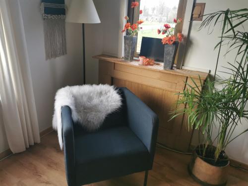 a blue chair with a white furry pillow on it at B&B In De Backerije 2 in Zuidwolde