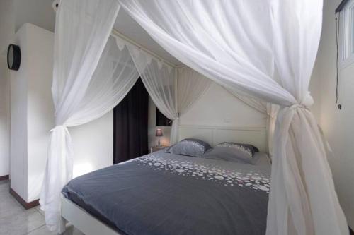 a bedroom with a canopy bed with white drapes at Eden plage in Les Trois-Îlets