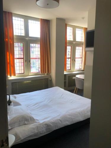 a bedroom with a white bed and windows at Hotel Salvators in Bruges