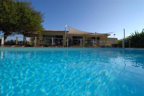 a large swimming pool in front of a building at location de vacances figuier avec jardin barbecue piscine chauffée à Calvi in Calvi
