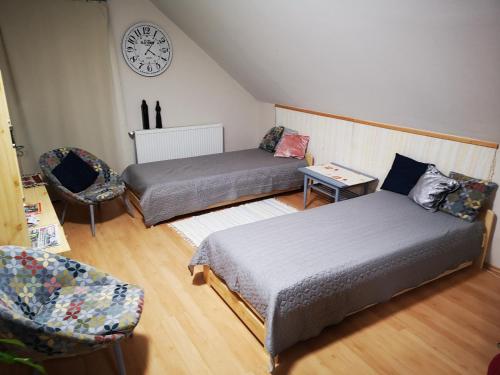 カポシュヴァールにあるÁgnes Apartmanのベッド2台と壁掛け時計が備わる客室です。