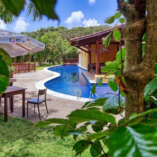una piscina con una mesa y una silla junto a una casa en Bosque da Praia Chalé 5, en Pipa