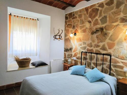 1 dormitorio con cama y pared de piedra en Alojamiento Rural Medios Panes, en Puerto Alto