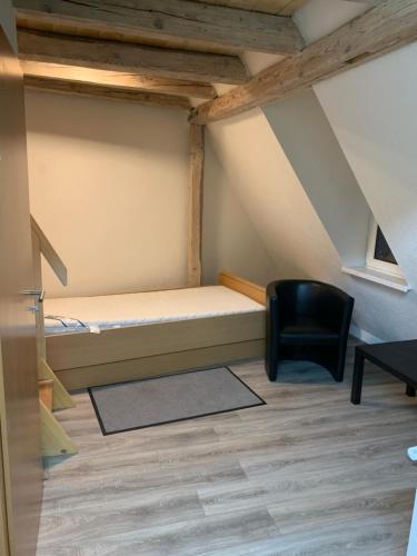 a small room with a bed and a black chair at Bürgerstüble in Donaueschingen