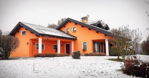 an orange house with snow on the ground at Bed & Breakfast Paradiso in Cesiomaggiore