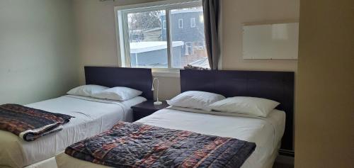 2 camas en una habitación con ventana en BUDGET LODGE, en Saskatoon