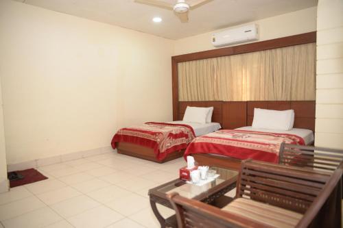 a hotel room with two beds and a bench at Stay Inn Guest House in Karachi
