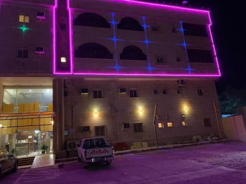 un edificio con luces púrpuras en el lateral. en Al Fanar Al Alamaya 3- Hay'aa Malakeya entrance, en Yanbu