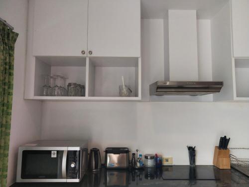a kitchen with white cabinets and a microwave at The Phura Villa Khaolak - SHA Extra Plus in Khao Lak