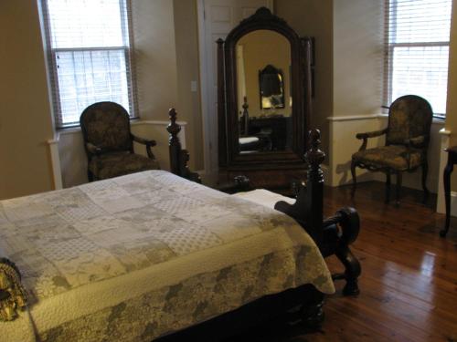 a bedroom with a bed and two chairs and a mirror at Clyde Hall Bed and Breakfast in Lanark