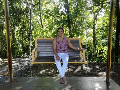 a woman sitting on a bench in a park at Confort Arenal in Fortuna