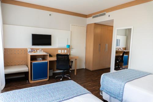 a hotel room with two beds and a desk at Quality Faria Lima in Sao Paulo