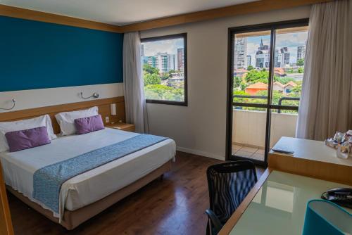 a hotel room with a bed and a desk and a window at Quality Faria Lima in Sao Paulo