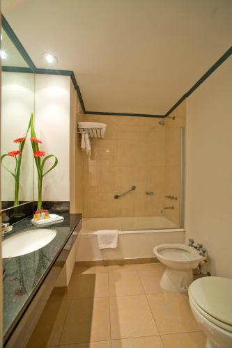 a bathroom with a tub and a toilet and a sink at Hotel Libertador in Tandil