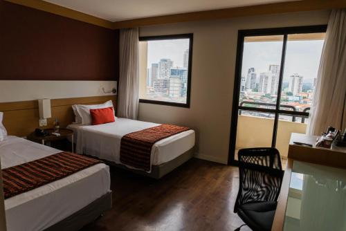 a hotel room with two beds and a large window at Quality Faria Lima in Sao Paulo