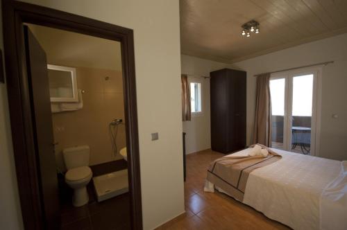 sypialnia z łóżkiem oraz łazienka z toaletą w obiekcie Lefkas Petra w mieście Agios Nikitas