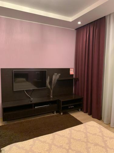 uma sala de estar com televisão e cortinas vermelhas em Квартира em Dnipro