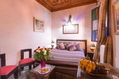 Un dormitorio con una cama y una mesa con un bol de fruta en Riad Lalla Khiti, en Marrakech