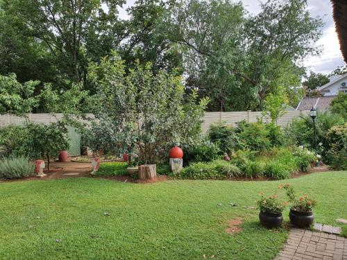 a yard with a garden with a tree and a fence at Chic Breeze in Bloemfontein