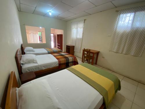 a bedroom with two beds and a chair in it at Hostal Vista al Mar in Puerto Ayora