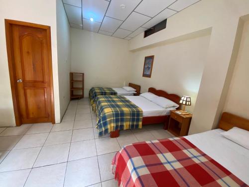 a hotel room with two beds and a door at Hostal Vista al Mar in Puerto Ayora