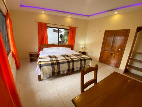 a bedroom with a bed and a table and a window at Hostal Vista al Mar in Puerto Ayora