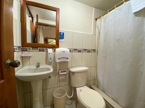 a bathroom with a toilet and a sink and a mirror at Hostal Vista al Mar in Puerto Ayora