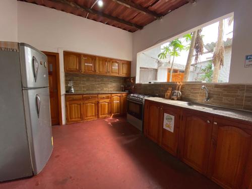a kitchen with wooden cabinets and a stainless steel refrigerator at Hostal Vista al Mar in Puerto Ayora